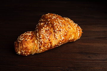 Croissant with sesame seeds isolated on a wooden background.