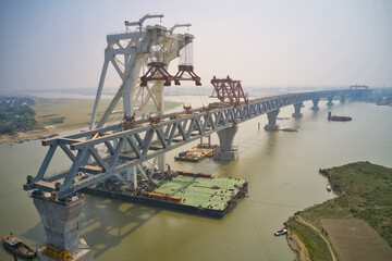 Aerial view of a building site while assembling the Padma bridge, the longest rail and highway bridge in Bangladesh crossing the Padma river, Zajira, Dhaka, Bangladesh.