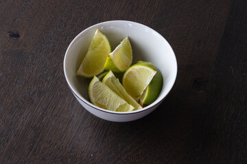 Lime wedges inside of a white bowl 