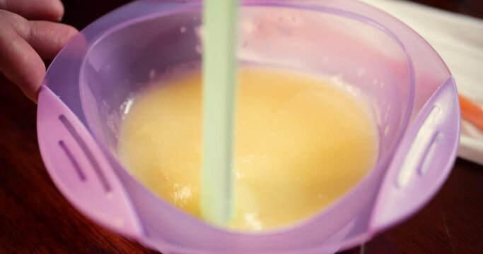mother prepares baby porridge at home. slow motion