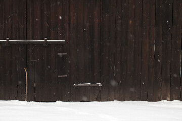 Winter. Fragment of an old wooden barn and falling snowflakes.
