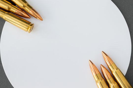 Bullets at corners of white circle on gray paper background. Cartridges 7.62 caliber for Kalashnikov assault rifle, closeup banner with copy space
