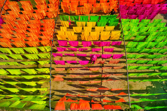 Aerial view of a woman hanging colourful cloth on thread for drying near Araihazar, Dhaka district, Bangladesh.