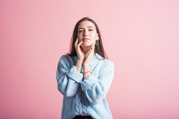 Portrait of a young brunette girl in the studio on a pink background