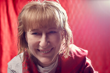 Portrait of fun middle-aged woman on a white background. Unprofessional female model with shy smile awkwardly posing in the Studio.