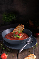 Tomato soup in a blue bowl with toast bread on a wooden table