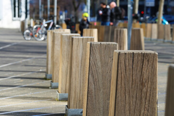 Closeup of isolated wood bollards in a row on urban street (focus on second bollard)