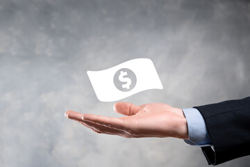 Businessman man holding money coin icon in his hands.Growing money concept for business investment and finance. USD or US dollar on dark tone background.