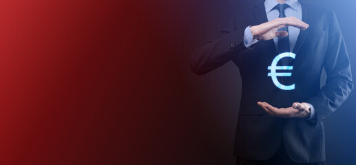 Businessman holds money coin icons EUR or Euro on dark tone background..Growing money concept for business investment and finance
