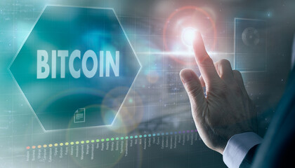A businessman controlling a futuristic display with a Bitcoin business concept on it.