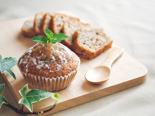 Banana cake sliced on, Cutting board and wooden spoon, Decorate on top with Peppermint leaf and icing sugar with copy space, Activity or hobby making Cupcake at home.