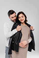 Man wearing jacket on smiling pregnant woman isolated on grey