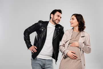 Pregnant woman smiling at husband isolated on grey