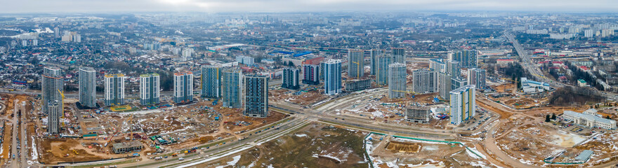 Fototapeta na wymiar Panoramic view of construction of high-rise resedential buildings. The construction industry with working equipment. View from above. Eye bird view of new resedential district.