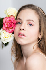Little pretty girl in pink holds the bouquet of roses. Close up the flowers and face. Beautiful little girl with flowers