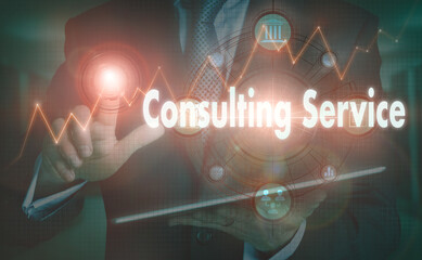 A businessman operating a computer display with a Consulting Service business word concept on it.