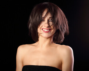 Happy toothy laughing bright makeup woman shaking her black short hair on black background. Closeup portrait