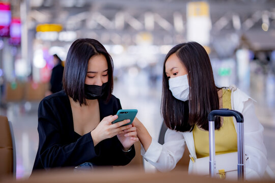 Two Young Asia Women Using Smartphone In The Airport