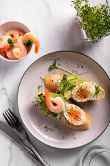 Breakfast with bruschetta with shrimps, eggs and microgreens in a plate