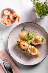 Breakfast with bruschetta with shrimps, eggs and microgreens in a plate