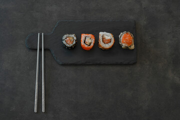 Top view of Japanese rolls on black concrete tray on dark background 