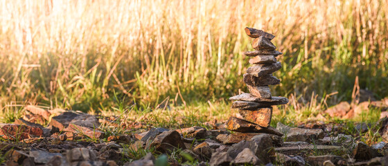 A small pile of stones stacked on the hiking trail lit by the rays of the sun.