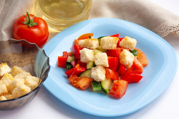 Healthy lunch, vegetable salad with crackers in a blue plate, tomato and olive oil in a bottle