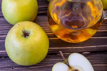 Green apples and jug with apple juice on wooden background