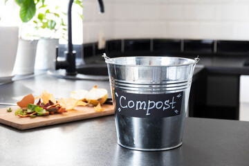 Metal bucket for composting with residue vegetables in modern light kitchen. Recycling concept....