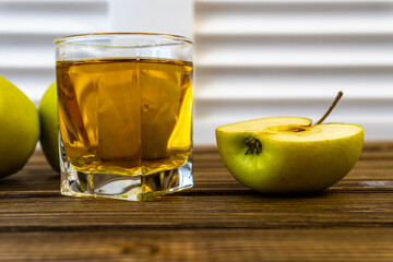 Green apples and glass with apple juice on wooden background