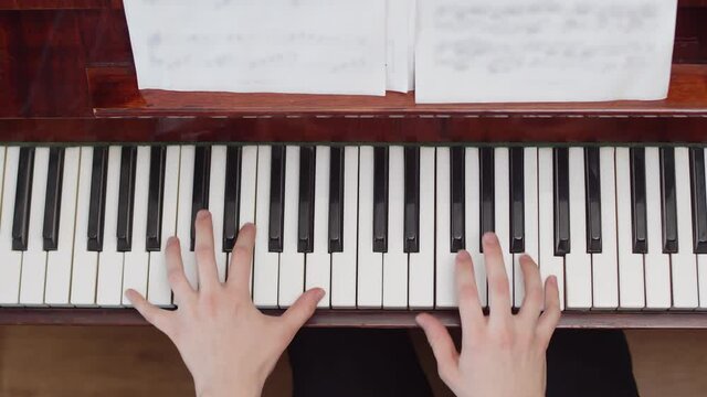 Musician playing the piano with his hands, top view. Artist plays chords according to notes on piano keys. Concept musical education.
