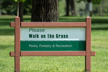 Sign in the park encouraging people to walk on the grass.