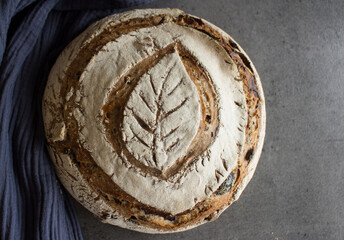 Sourdough bread made of whole grain with nuts, raisins and olives. Beautiful decorated fresh bread. Healthy living concept. 
