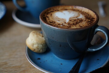 stimmungsvoller Cappucino in einem atmopshärischem Kaffee mit Keks daneben