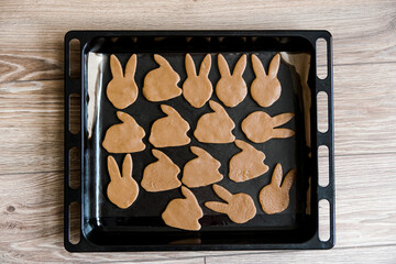 Raw easter gingerbread dough. Dough in the form of easter bunnies on the baking sheet. Preparation of Easter cookies