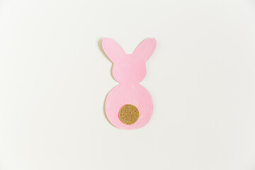 Easter pink paper bunny with golden tale on the white background. Minimalist Easter concept