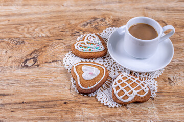 Homemade heart-shaped cookies, with white icing and sprinkles with coffee