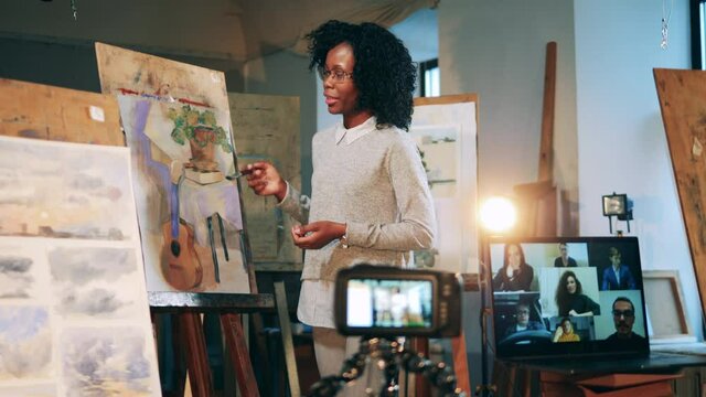 African woman is teaching her online students how to paint