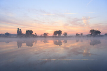 Fototapeta na wymiar Pink foggy dawn on the misty lake