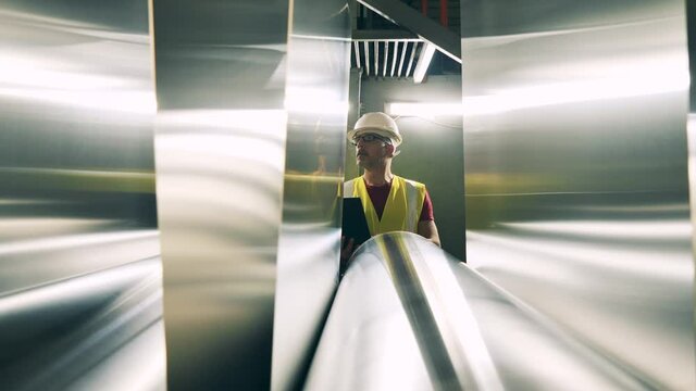 Male engineer is watching metal facing sheets getting relocated