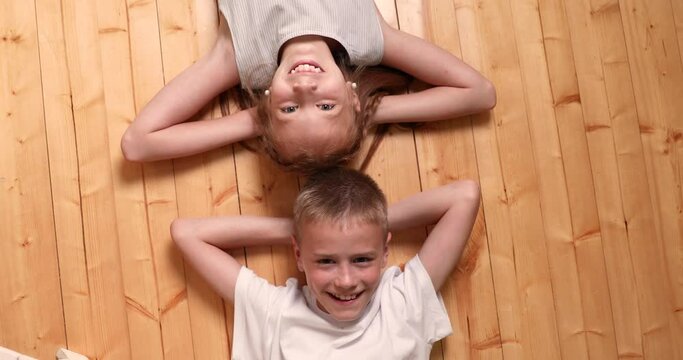 the brother and the sister lie on a floor. girl and boy. children laugh