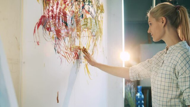A woman is using her both hands to paint on a wall