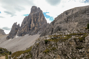 A panoramic view on Italian Dolomites. There are many high and sharp peak in front, with many landslides. Dangerous climbing. Barely any plants growing in the  area. Raw and unspoiled landscape.