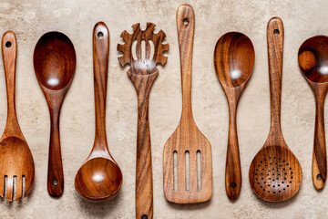 Various wooden kitchen utensils on a light concrete background top view. 