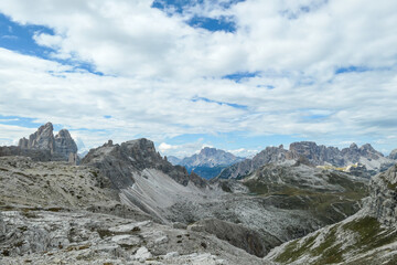 A panoramic view on a valley in Italian Dolomites. There is a massive mountain in front, with very...
