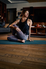 A middle-aged woman doing yoga at home.