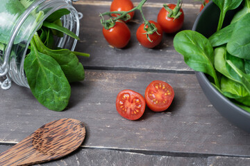 Organic bio food vegetables on rustic wooden background.Fresh spinach in bowl and glass jar with cherry tomatoes.