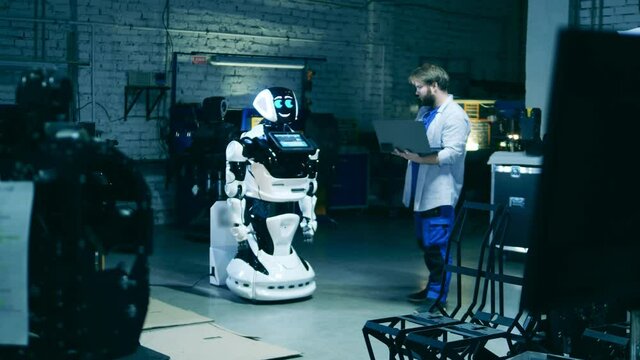 Male specialist is observing a cyborg in the workshop