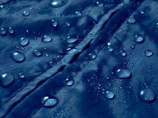 Water drops on waterproof membrane fabric. Detail view of texture of blue waterproof cloth.
