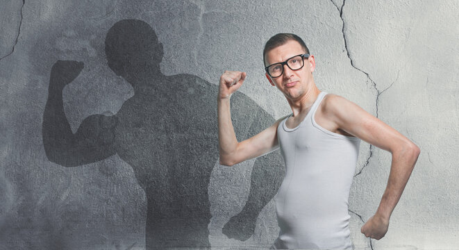 Portrait of a funny skinny bodybuilder. Humorous sportsman using small dumbbells for bodybuilding